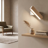 Angled wood bar wall sconce lighting a pale wall above a shelf