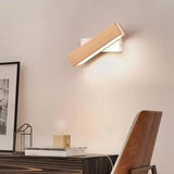 Oak bar sconce tilted down over a framed picture and desk