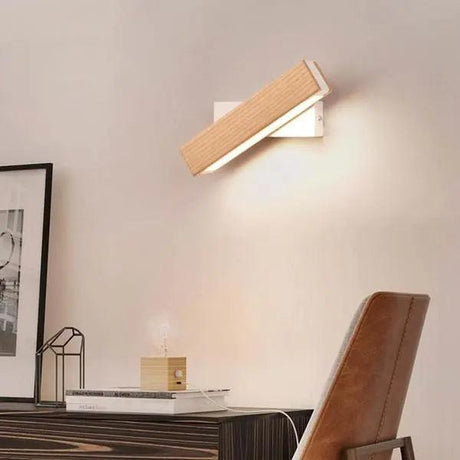 Oak bar sconce tilted down over a framed picture and desk