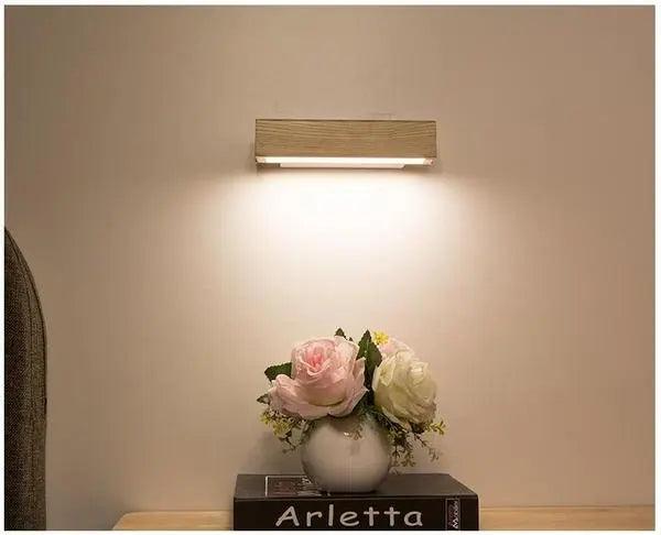 Wood sconce mounted straight above a vase of pale roses