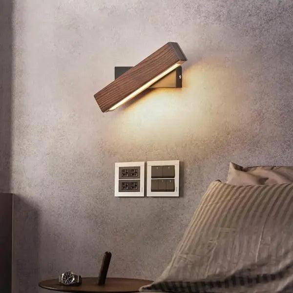 Walnut sconce angled upward against a grey concrete bedroom wall