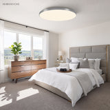 Round LED ceiling light in a bright bedroom with timber dresser