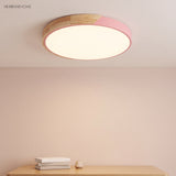 Pink round LED ceiling light with a wood rim seen close above a console table