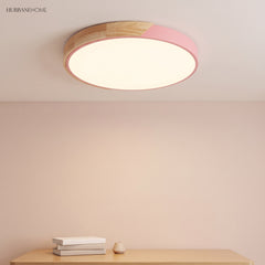 Pink round LED ceiling light with a wood rim seen close above a console table