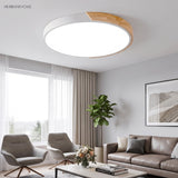 White and wood round LED ceiling light above a living room with grey armchairs