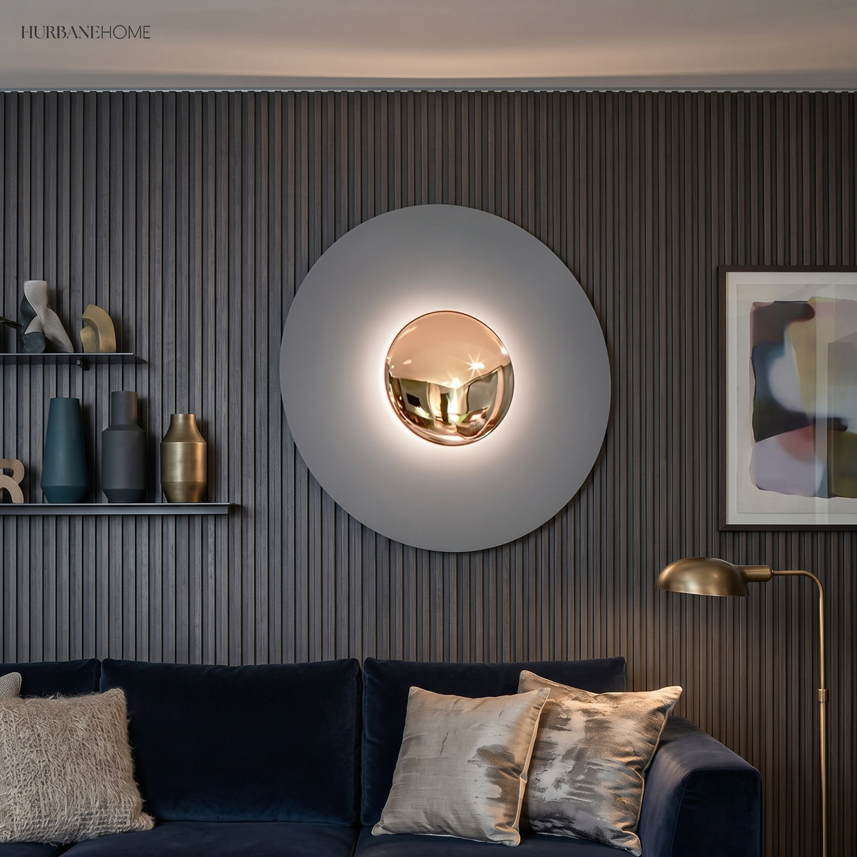 Grey disc wall sconce with a gold centre lit above a blue sofa