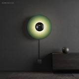 Green disc sconce with a chrome centre lit on a dark wall
