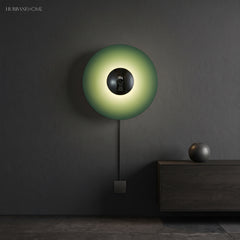 Green disc sconce with a chrome centre lit on a dark wall