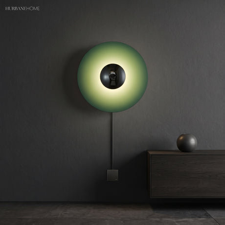 Green disc sconce with a chrome centre lit on a dark wall