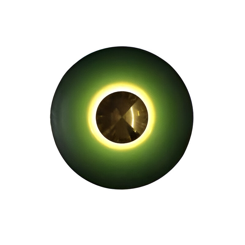 Green disc sconce with a gold centre lit on a white ground