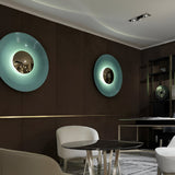 Two disc sconces in blue and green lit in a dark dining room