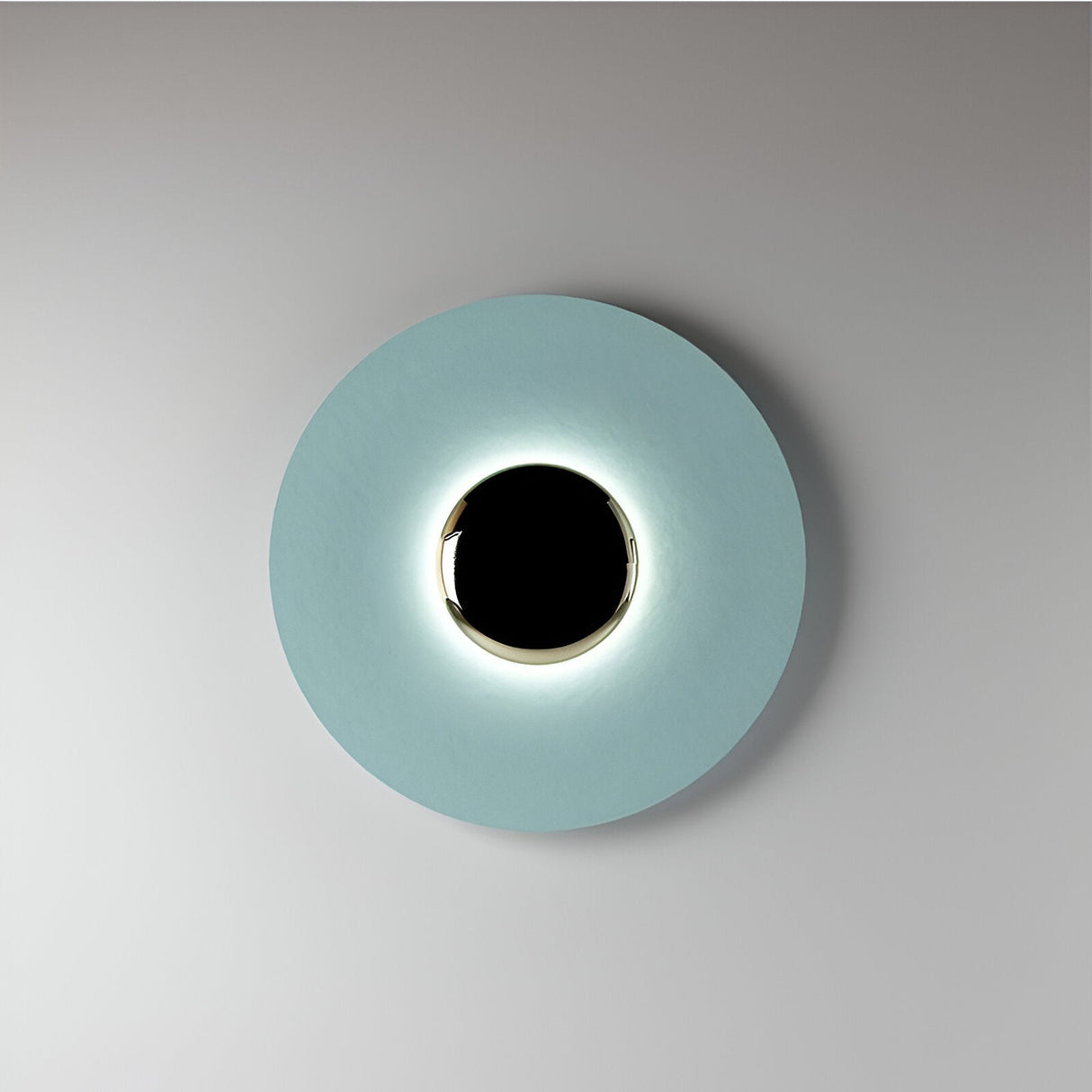 Blue disc sconce with a black centre lit on a pale wall