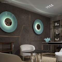 Two disc wall sconces in blue and green lit in a dining room