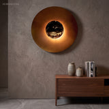Large orange disc sconce lit above a walnut sideboard
