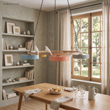 Round wood chandelier with three bird figures above a dining table by shelving