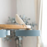 Lifestyle view of the round wood bird chandelier lighting a calm modern interior