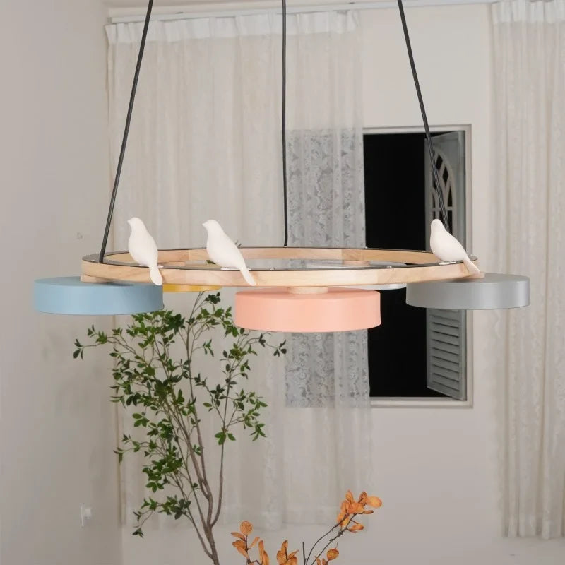 Round wood bird chandelier with colourful drum shades and slim black suspension cables