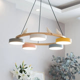 Angled view of the round wood chandelier with pastel drum shades and a perched bird