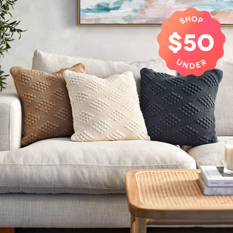 Gray sofa with textured throw pillows and a 'Shop $50 Under' label.