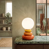 Stacked ceramic lamp lit on a green marble counter in front of a window