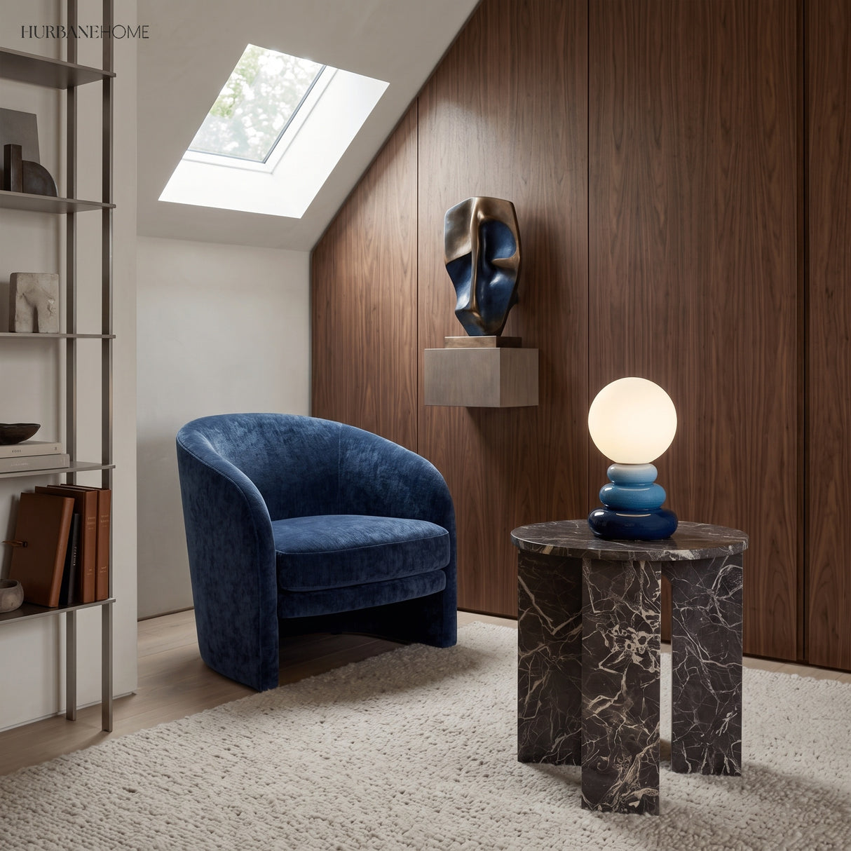 Blue stacked ceramic lamp on a dark marble side table beside a velvet chair