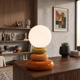 Orange stacked ceramic lamp with round opal shade on a walnut sideboard
