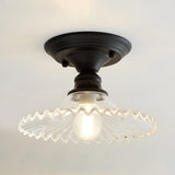 Clear ribbed scalloped ceiling light glowing warm on a white ceiling