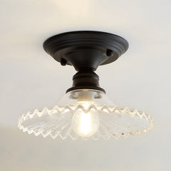 Clear ribbed scalloped ceiling light glowing warm on a white ceiling