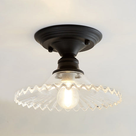 Clear ribbed scalloped ceiling light glowing warm on a white ceiling
