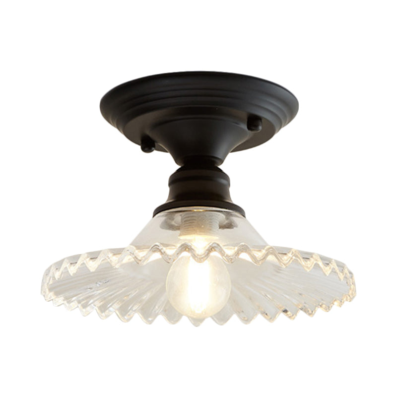 Clear ribbed scalloped ceiling light lit warm on a plain background