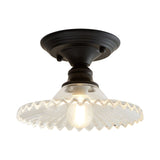 Clear ribbed scalloped ceiling light lit warm on a plain background