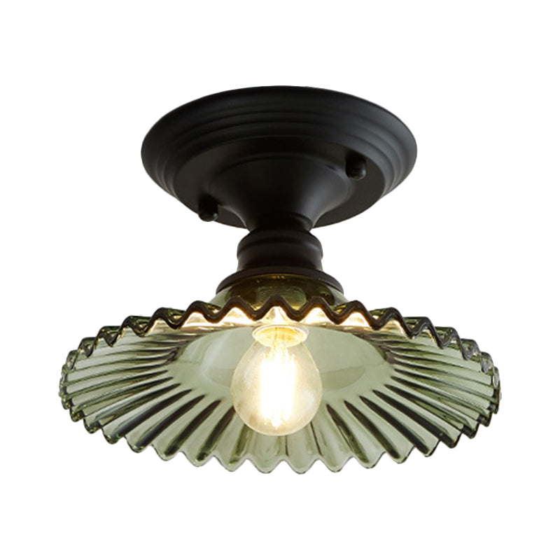 Green ribbed scalloped ceiling light lit warm on a plain background
