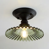 Green ribbed scalloped shade and dark canopy on a pale background
