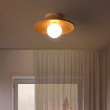 Wood ceiling light glowing warm beside a sheer curtained window