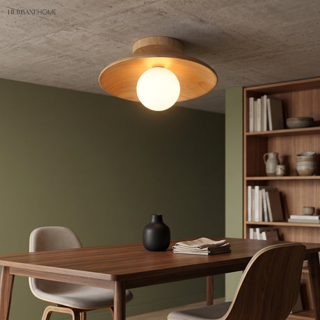 Wood ceiling light lit above a dining table on a green wall