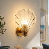 Transparent glass shell sconce shown on a plain studio background