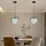 Two green glass globe pendants in different sizes hanging over a living room seating area