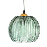 Single green palm leaf glass globe pendant shown as an eco friendly boho decor piece