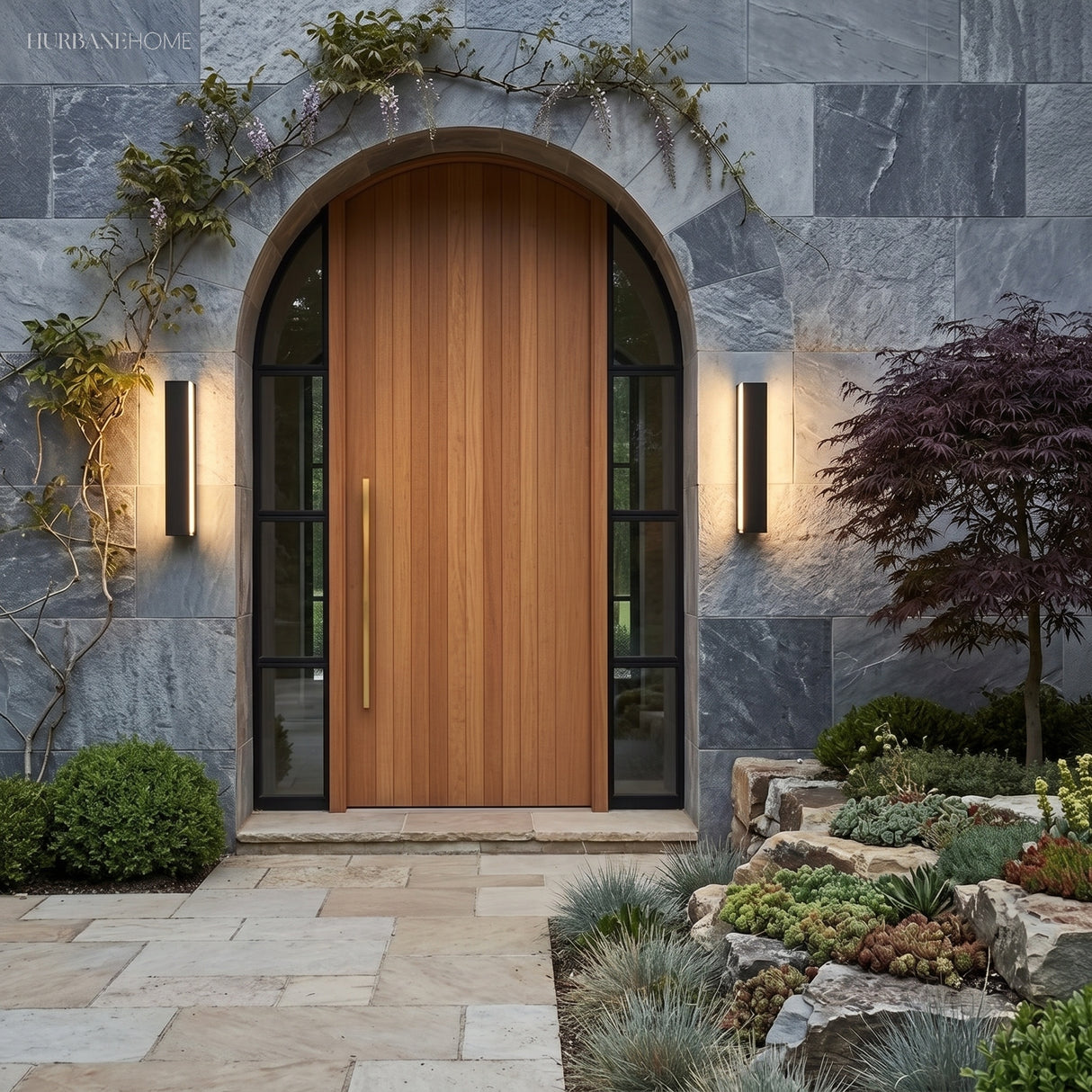 Pair of linear lights flanking an arched timber front door in stone cladding