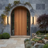 Pair of linear lights flanking an arched timber front door in stone cladding