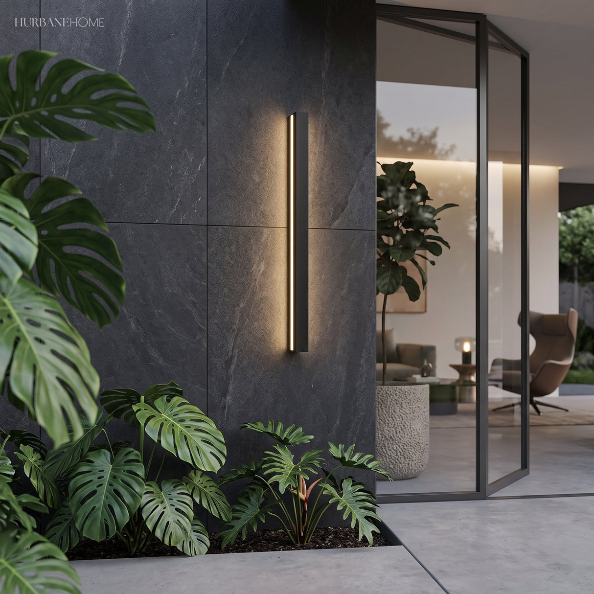 Tall linear wall light on dark stone beside foliage and a glazed living room