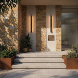 Two linear wall lights on stone and render beside a lit entrance stairway