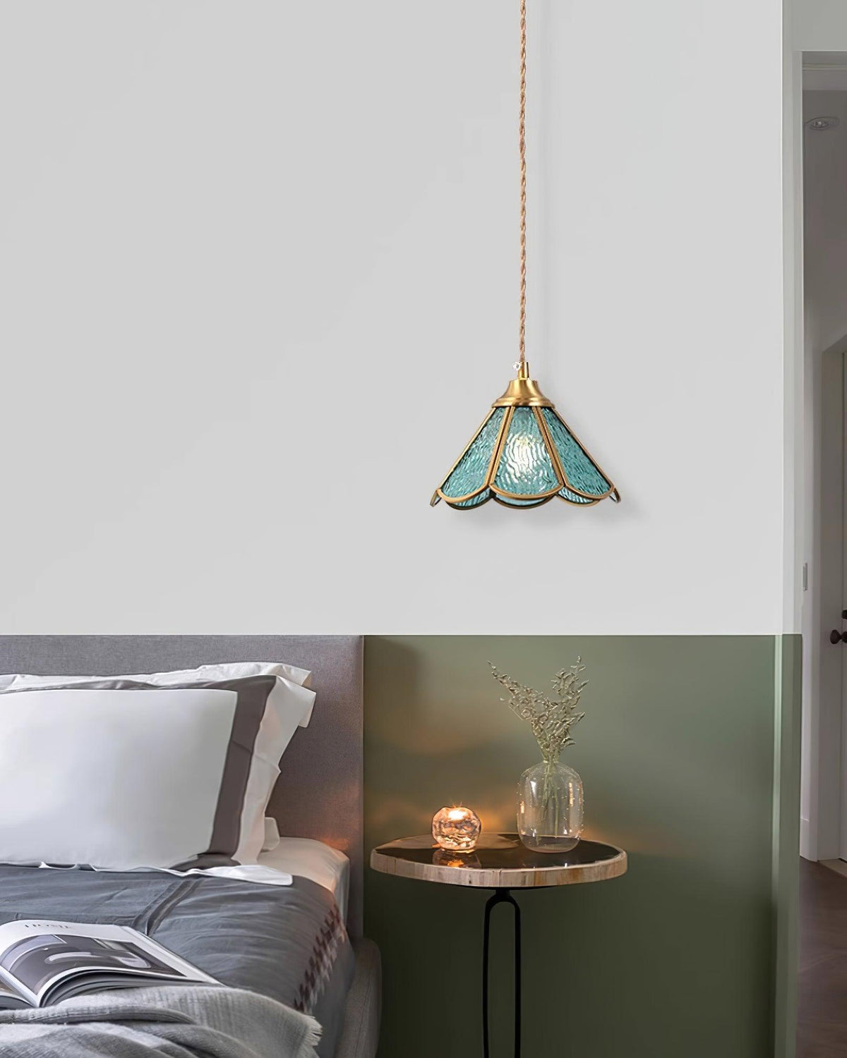 Small blue glass pendant above a bedside tray table in a green bedroom