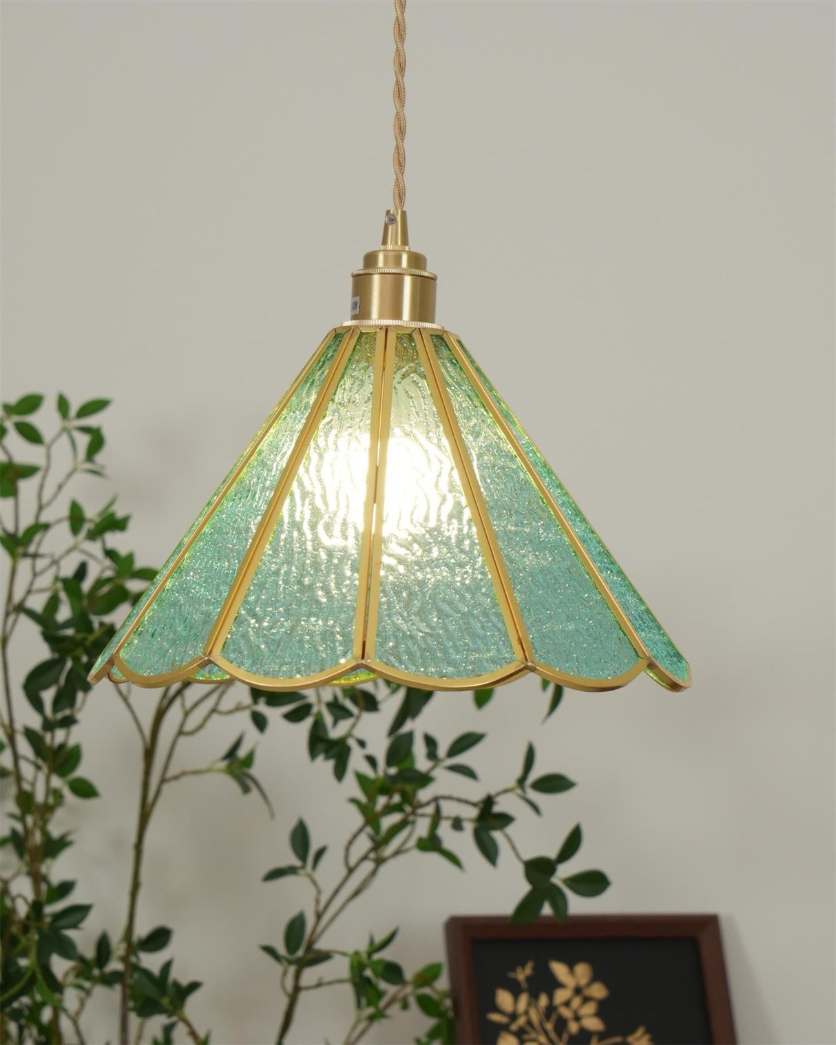 Small blue glass pendant hanging in a corner beside a leafy houseplant