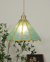 Small blue glass pendant hanging in a corner beside a leafy houseplant