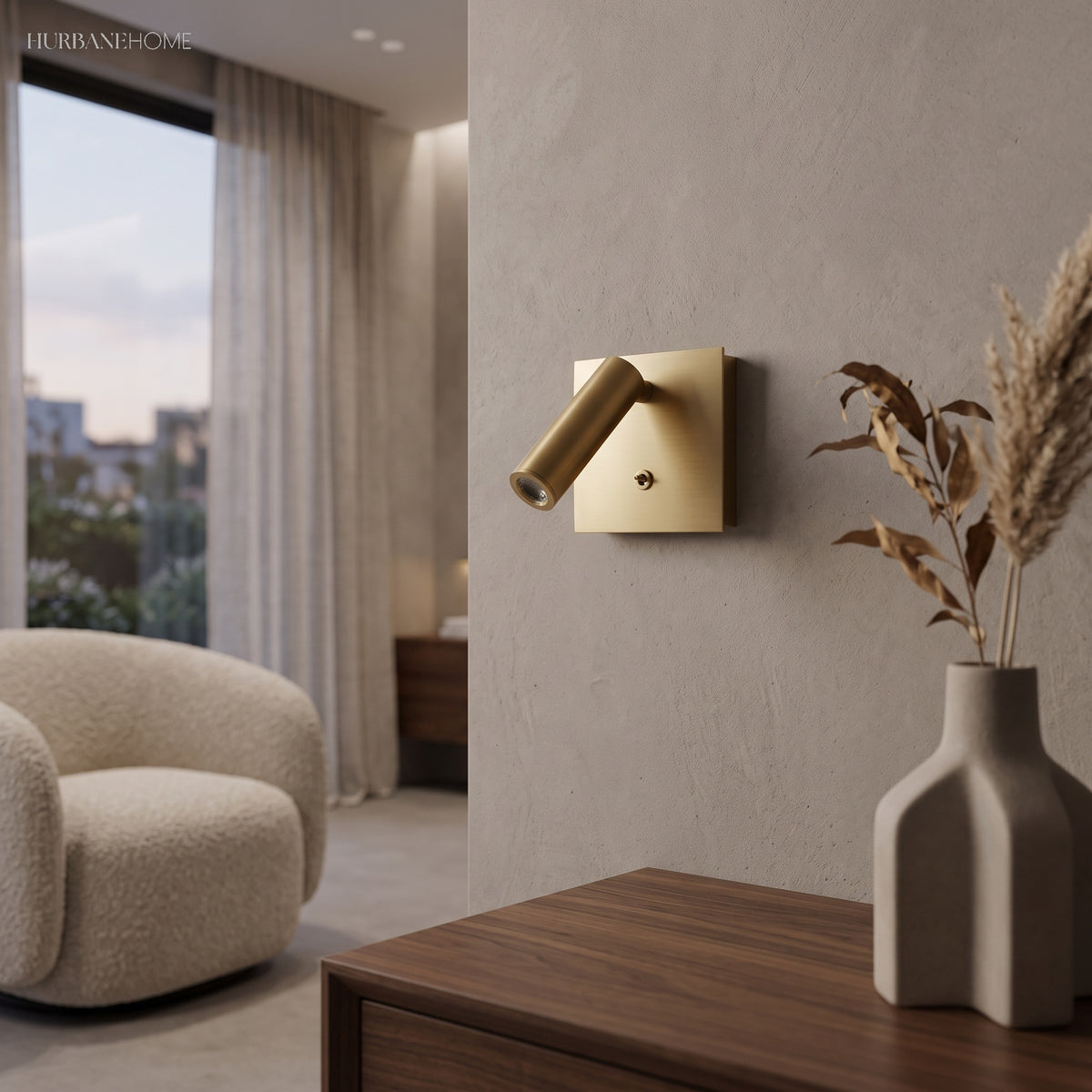 Copper square wall sconce beside a curved armchair and dried grasses