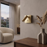 Copper square wall sconce beside a curved armchair and dried grasses