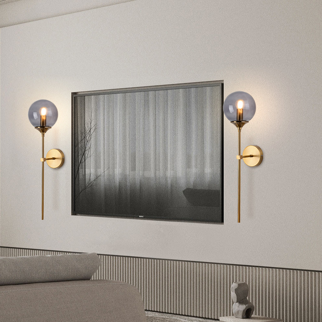 Smoke grey glass globe wall sconce on a brass stem front view