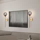 Smoke grey glass globe wall sconce on a brass stem front view
