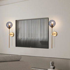 Smoke grey glass globe wall sconce on a brass stem front view